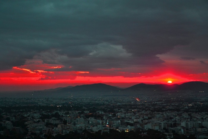 Athens cityscape at sunset with dramatic red clouds
