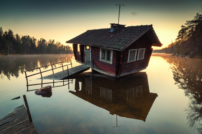 A tilted wooden house on a lake in Finland