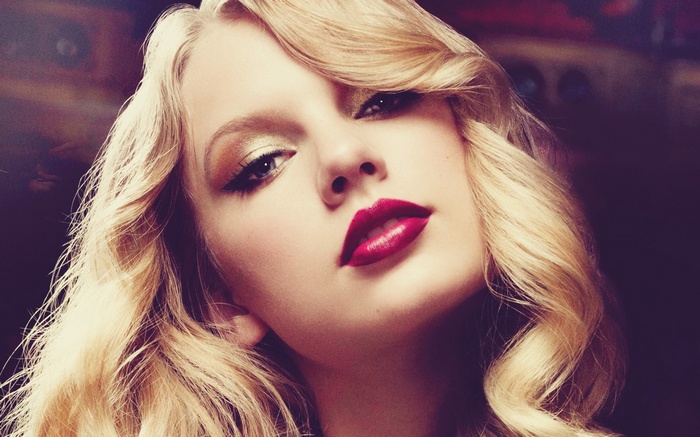 Taylor Swift with blonde curly hair and red lipstick