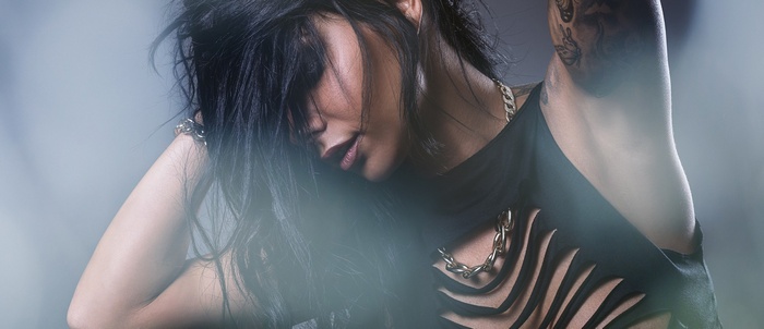 Woman with black hair and tattoos wearing ripped black clothing