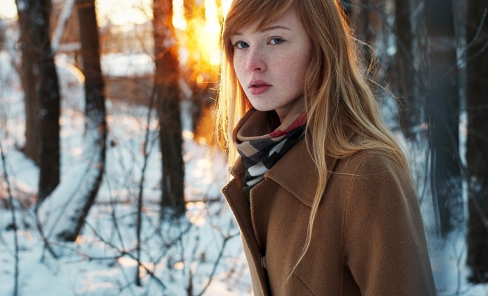 Young woman with freckles in a snowy forest