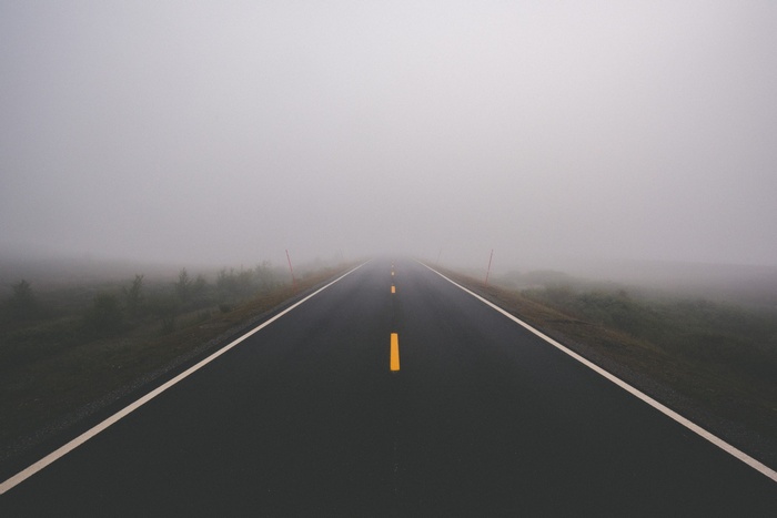 A foggy road with yellow lines