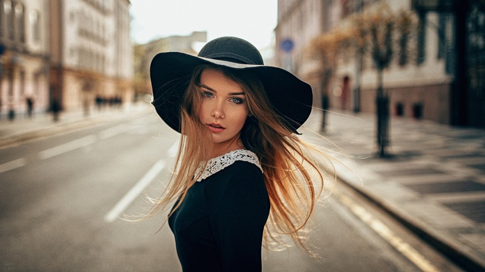 Woman in a black hat and dress on a city street