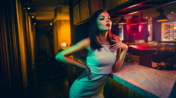 Woman in white dress at a bar with colorful lights