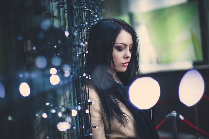 Woman with black hair and smoky eyes near lights