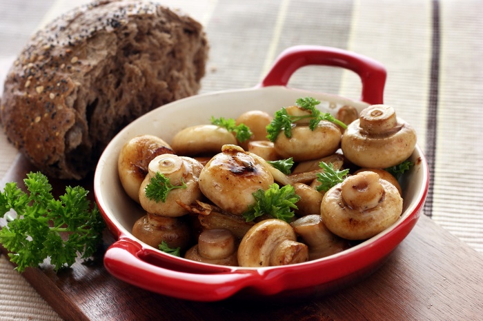 Cooked mushrooms in a red bowl with parsley and bread