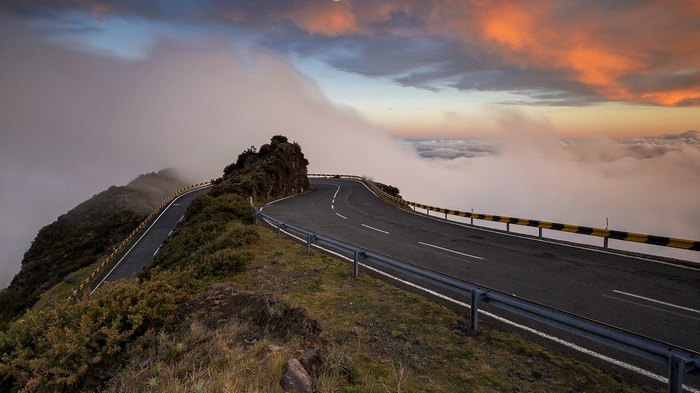 Winding mountain road above the clouds at sunset