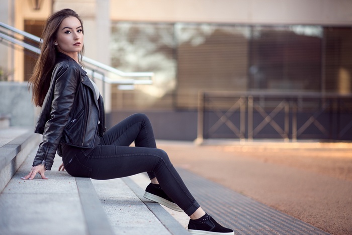 Woman in leather jacket sitting on stairs