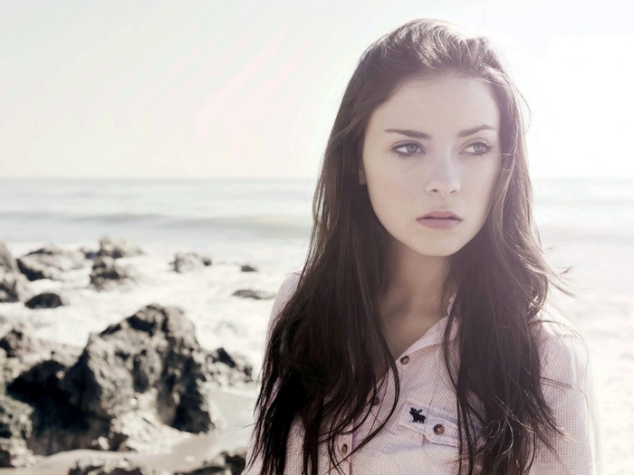 Alexandra Tyler on a rocky beach with the sea in the background