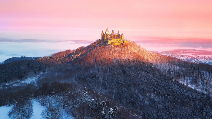 Burg Hohenzollern castle on a snowy mountain at sunrise
