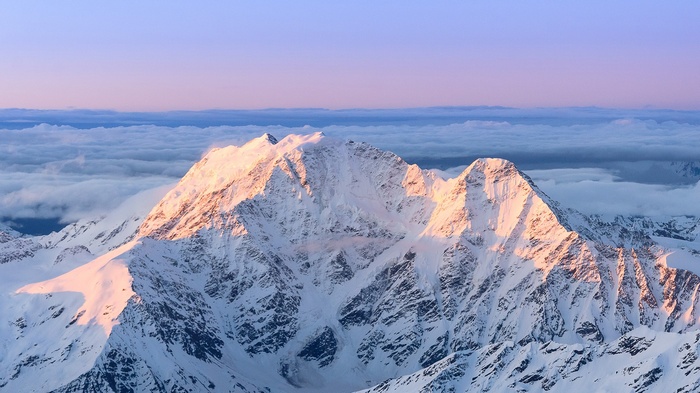 Snow-covered mountains at sunrise above clouds