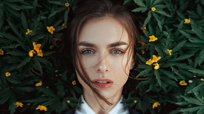 Portrait of Victoria Vishnevetskaya among green leaves and yellow flowers