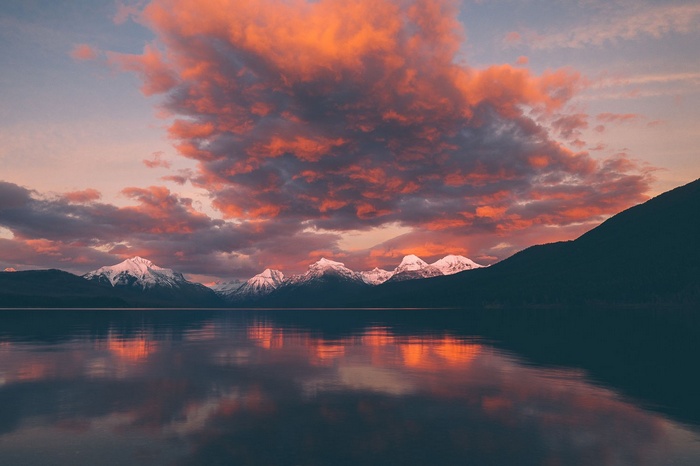 Snow-capped mountains reflected in a lake at sunset