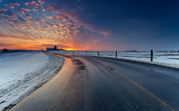 Road through a snowy landscape at sunset