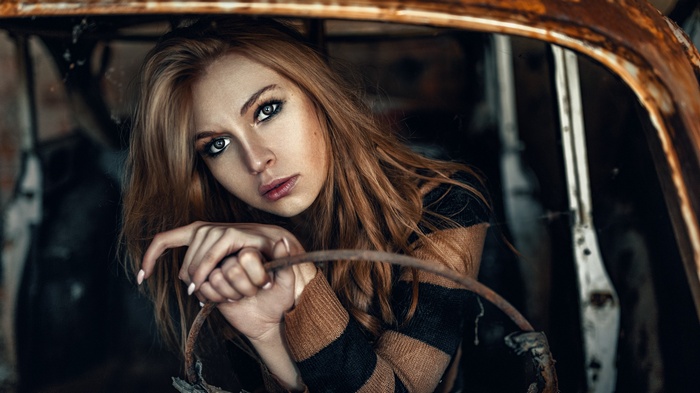 Carla Sonre posing in a rusty car