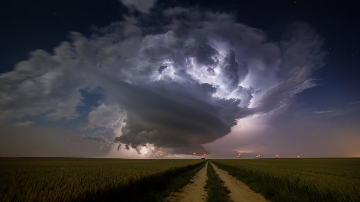 Supercell storm with lightning over a field at night