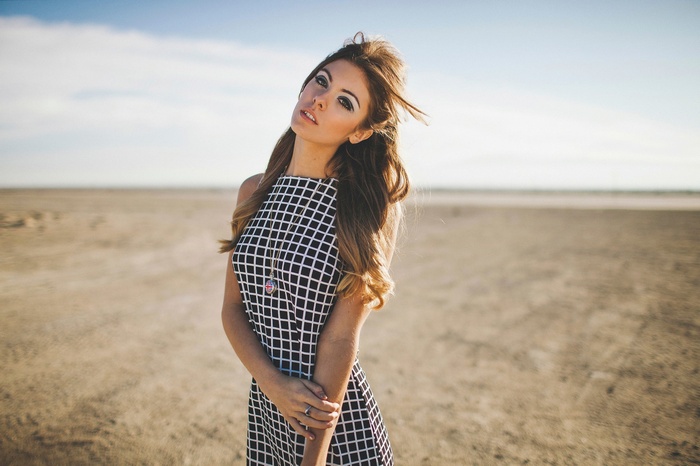 Woman with auburn hair in a checkered dress on a beach