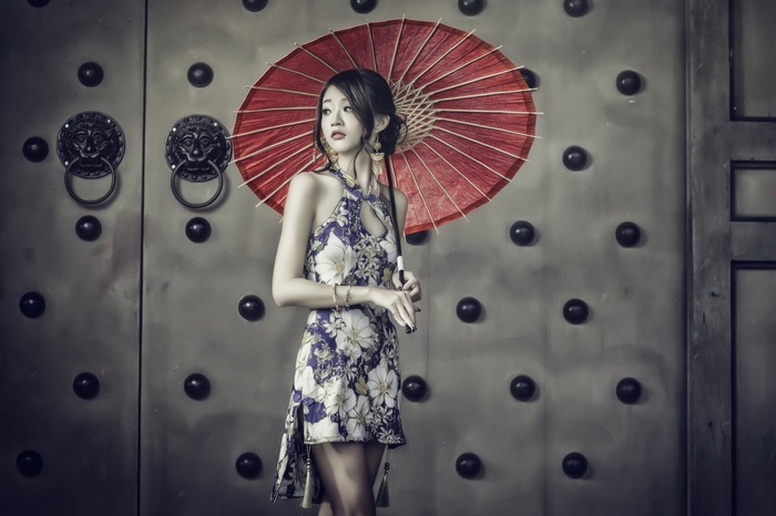 Asian woman in a floral dress holding a red umbrella