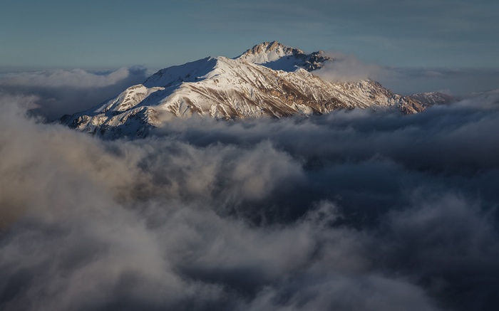 Snow-capped mountains emerge from clouds