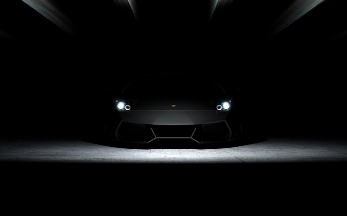 Black Lamborghini with headlights on in dark garage
