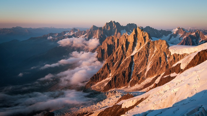 Sunrise over jagged mountain peaks with clouds