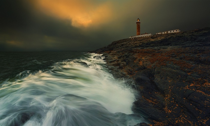 Lighthouse on a rocky coast with stormy seas