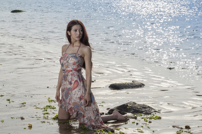 Asian woman kneeling on a sandy beach