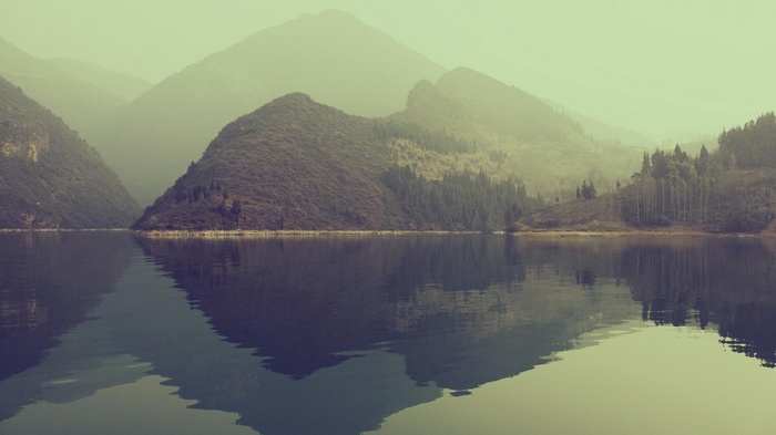 Misty mountains reflected in a calm lake