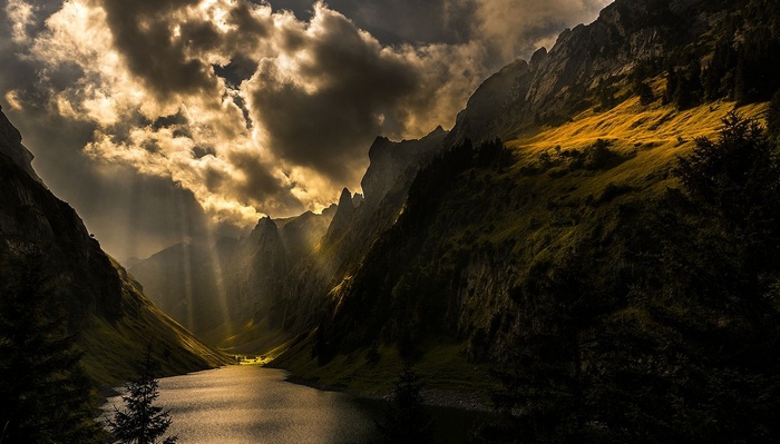 Sun rays over a mountain lake with dramatic clouds