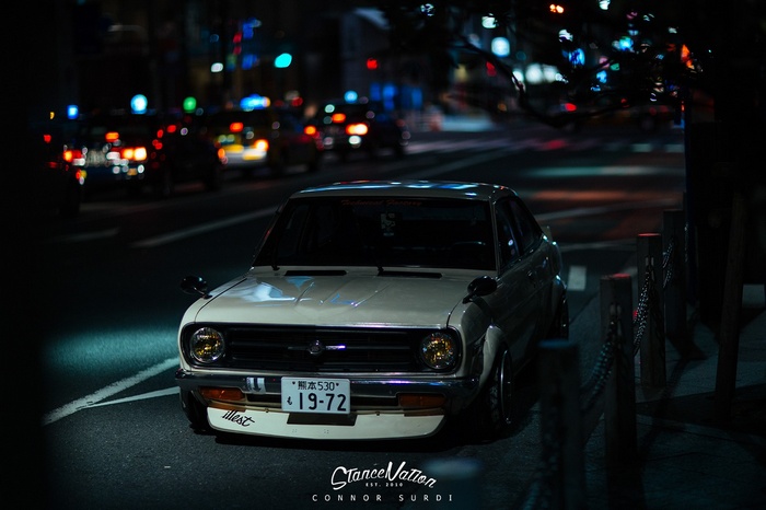 Datsun coupe parked on a city street at night