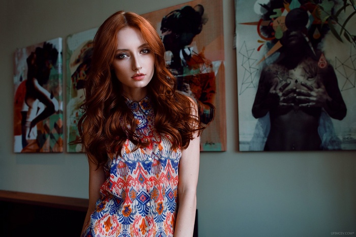 Redhead woman in patterned dress in front of art