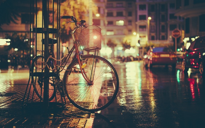 Bicycle parked on a wet city street at night