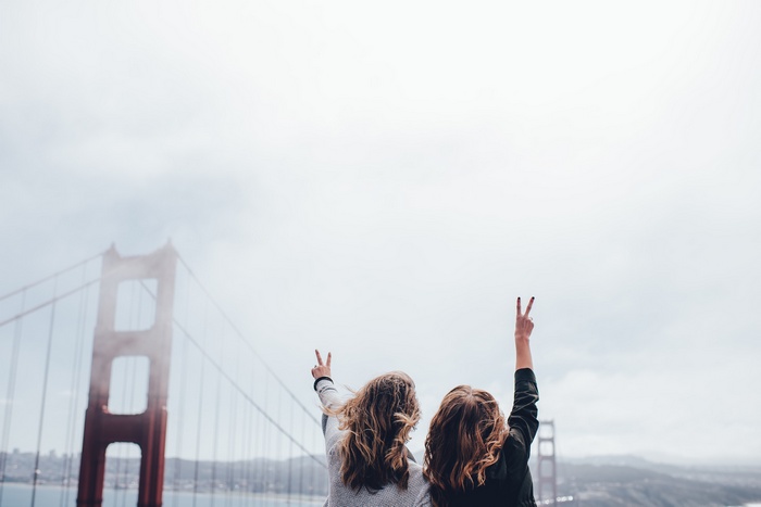 Two women making peace signs at the Golden Gate Bridge