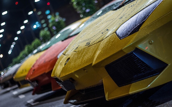 Yellow Lamborghini cars parked in the rain at night