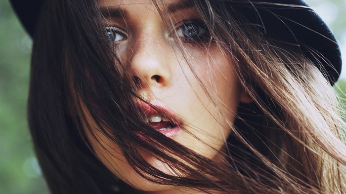 Woman with dark hair and blue eyes wearing a hat