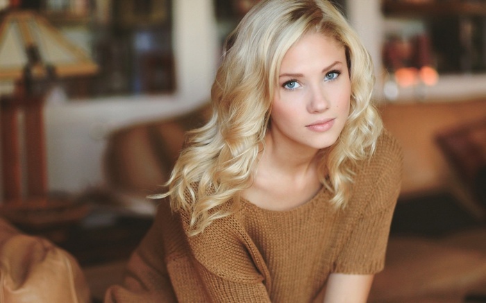 Woman with blonde hair wearing a brown sweater