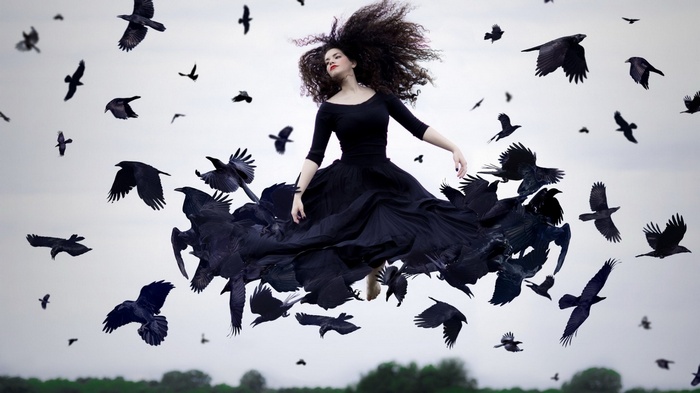 Woman in black dress surrounded by flying crows