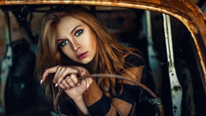 Woman in a striped sweater inside a rusty car