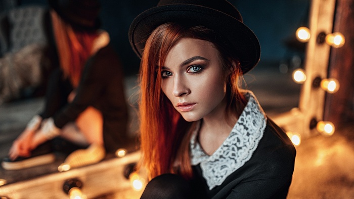 Redhead woman with blue eyes wearing a hat and black dress