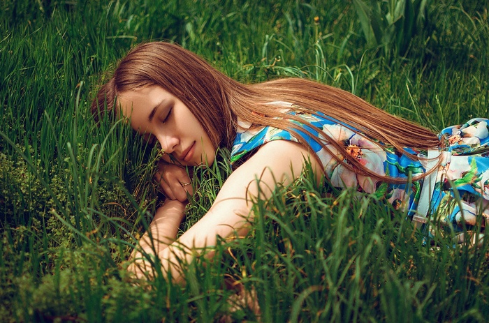 Woman in a floral dress sleeping in the grass