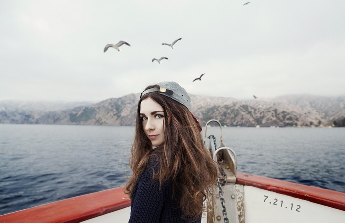 Woman on a boat with seagulls and mountains