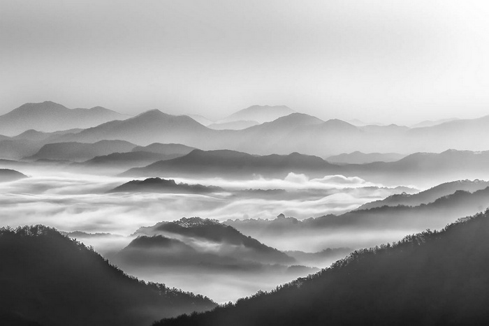 Monochrome mountains shrouded in mist at sunrise