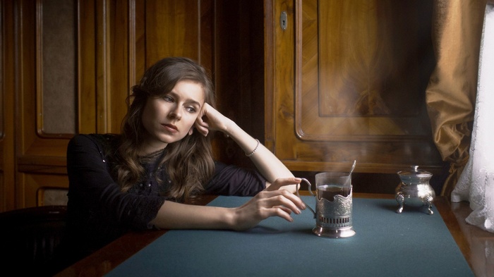 Woman with long hair sitting at a table with tea