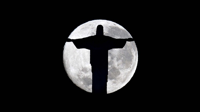 Christ the Redeemer statue silhouetted against the Moon