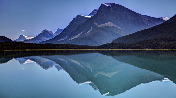 Mountains reflected in a calm lake with a forest