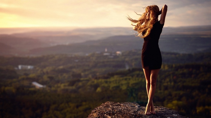 Woman in black dress on a mountain at sunset