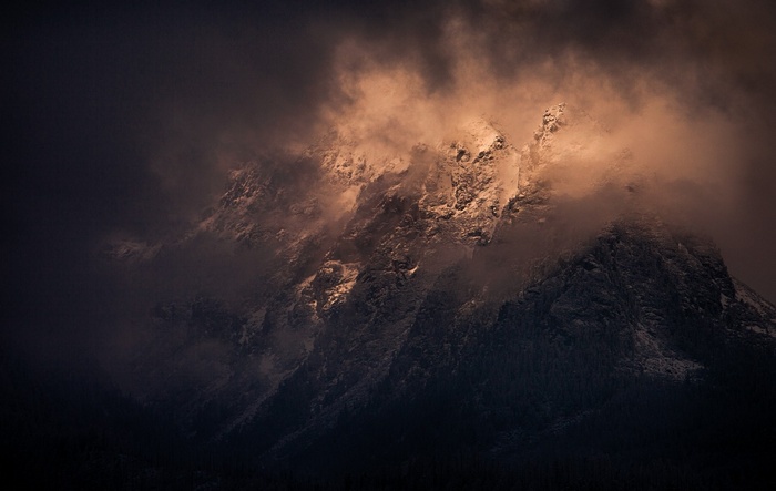 Sunlight on a snowy mountain peak through clouds