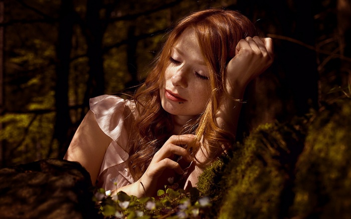 Redhead woman with freckles resting in a forest