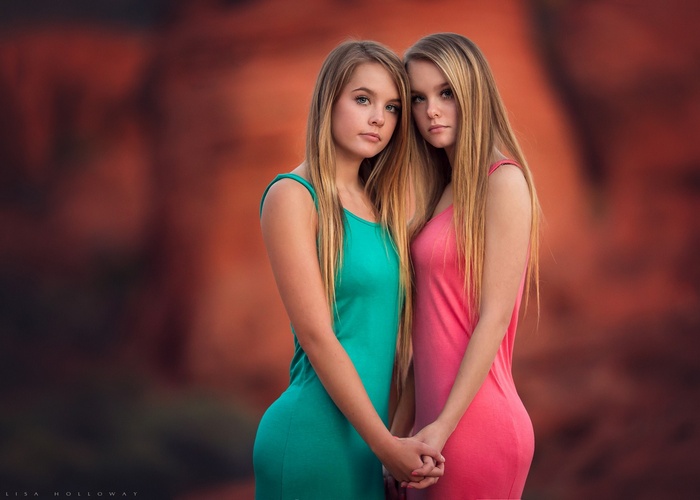 Two young women with long blonde hair holding hands