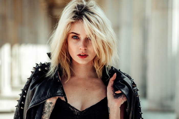Woman with blonde hair and tattoos wearing a leather jacket